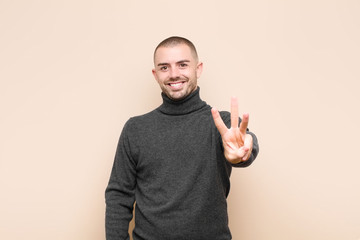 young handsome man smiling and looking friendly, showing number three or third with hand forward,...