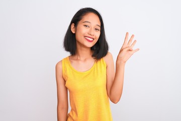 Young chinese woman wearing yellow casual t-shirt standing over isolated white background showing and pointing up with fingers number four while smiling confident and happy.