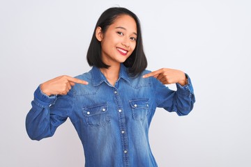 Young beautiful chinese woman wearing denim shirt standing over isolated white background looking...