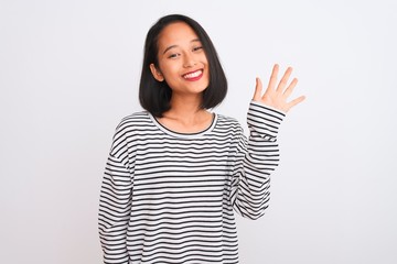 Young chinese woman wearing striped t-shirt standing over isolated white background showing and pointing up with fingers number five while smiling confident and happy.