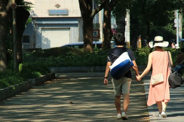 手をつなぐ二人が歩く夏の公園