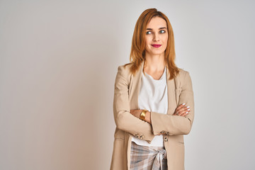 Redhead caucasian business woman standing over isolated background smiling looking to the side and staring away thinking.