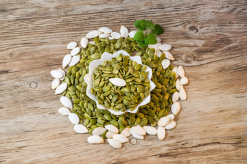 Peeled raw pumpkin seeds in a white plate on a wooden table theme healthy, vegetarian, vegan food, copy of space