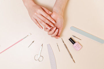 Medicine, cosmetology and manicure. A client in a nail salon demonstrates well-groomed nails after the procedure. White table with tools. Close up and flat line