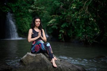 Yoga practice and meditation in nature. Woman practicing near river