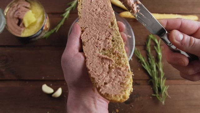 Cook spreading tasty poultry pate on French baguette or bread with a knife
