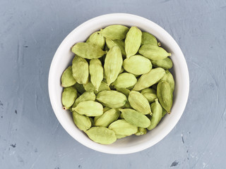Green cardamom in white bowl on a gray concrete background. Healthy eating concept