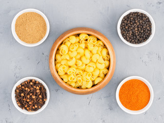 Pasta, black pepper, red chili, masala, cloves in bowl on a gray concrete background. Healthy eating concept