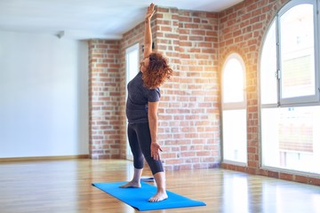 Obraz premium Middle age beautiful sportwoman on mat. Standing practicing yoga doing revolved triangle pose at gym
