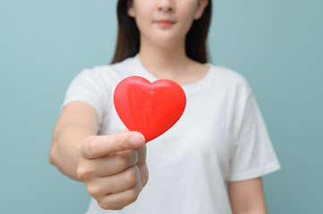 young women holding red heart isolated over Blue background.