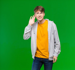 young blonde man looking serious and curious, listening, trying to hear a secret conversation or...