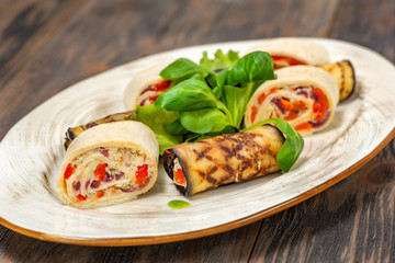 Rolls with fish and eggplant rolls with herbs on a plate