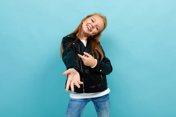 Fototapeta na wymiar Beautiful caucasian teenager girl in black jacket and jeans dances isolated on blue background