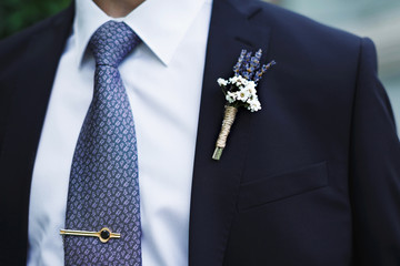 Boutonniere of unusual flowers on the groom's jacket.