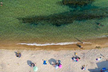 Fototapeta na wymiar Aerial view from flying drone of people crowd relaxing on the beach in Greece.