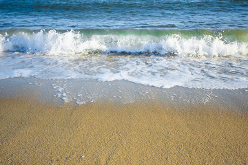 Soft foamy wave of ocean on sandy beach. Horizontal composition.