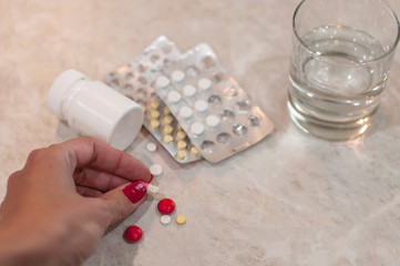 Various pills  and capsules in the hand of a woman who wants to drink them and recover