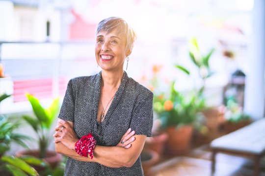 Middle age beautiful grey-haired woman wearing dress and bandana on wrist smiling happy and confident standing with a smile on face at terrace