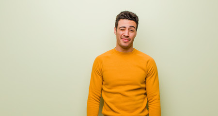 young arabian man looking happy and friendly, smiling and winking an eye at you with a positive...