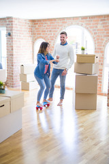Young beautiful couple playing with skate at new home around cardboard boxes