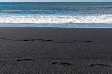 Footprints on black lava sand beach in Puerto Naos, La Palma, Canarian islands, Spain