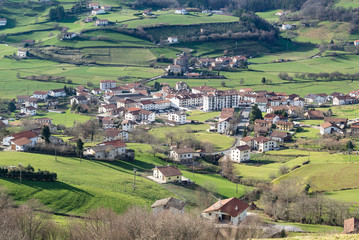 Fototapeta na wymiar Idyllic view of a white houses village surrounded by green meadows. Berastegi, Basque Country, Spain. 