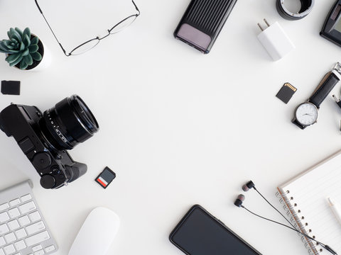top view of photographer work station, work space concept with digital camera, memory card, keyboard and smartphone on white table background