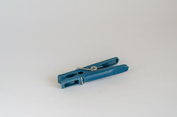 Blue plastic clothespin. Image of a single clothespin on a light background. Eye level shooting. Selective focus.