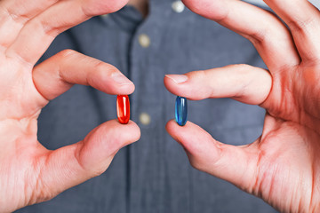 Man's hands close-up offering red and blue pills