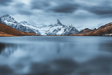 Moody picturesque view on Bachalpsee lake in Swiss Alps mountains. Snowy peaks of Wetterhorn, Mittelhorn and Rosenhorn on background. Grindelwald valley, Switzerland. Landscape photography