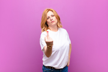 middle age woman feeling angry, annoyed, rebellious and aggressive, flipping the middle finger,...