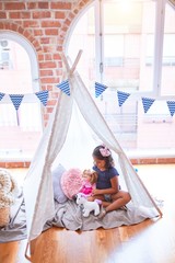 Beautiful toddler girl sitting on the floor playing with unicorn and doll inside  tipi at kindergarten © Krakenimages.com