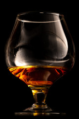 Glass of cognac on black reflective glass