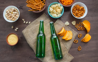 Fototapeta na wymiar Beer bottles with pretzels and various snacks. Beer snacks. Beer background. Wood background. View from above. Place for text.