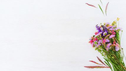 Floral background. Natural composition. Wildflower bouquet on white wooden textured surface.