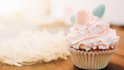 Confectionery art. Dessert decoration. Cupcake with white cream pastel egg shaped toppers.