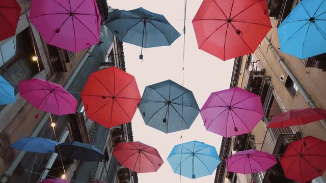 Colourful umbrellas are hanging on the rope between buildings