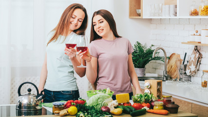 Women home party. Cooking leisure hobby. Two ladies preparing food drinking wine in kitchen.