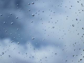 Raindrops on the glass against the blue sky with clouds.Clear blue sky with cumulus and cirrus clouds. Sunny weather. Joyful mood. High pressure. Clean air ecology. Water in a gaseous state