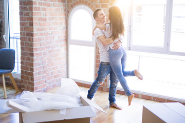 Young beautiful couple hugging at new home around cardboard boxes