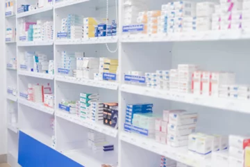Papier Peint photo Pharmacie Médicaments disposés dans des étagères, pharmacie au détail. Arrière-plan abstrait flou intérieur avec produit de santé sur armoire à pharmacie.