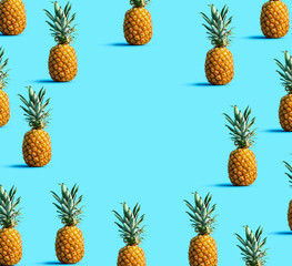 Round frame of pineapples on a solid color background