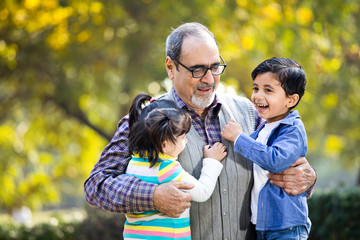 Grandchildren having fun with grandfather at park
