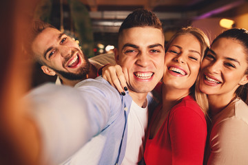 Group of young people having fun in a night out in billiards club and taking selfie