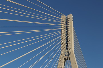 Obraz premium Rzeszow, Poland - 9 9 2018: Suspended road bridge across the Wislok River. Metal construction technological structure. Modern architecture. A white cross on a blue background is a symbol of the city