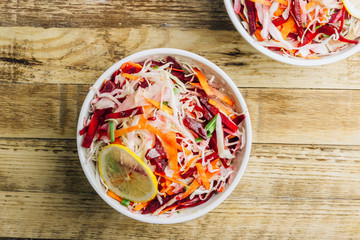 Spring healthy vegan salad with raw beet, carrot and cabbage in white bowls. Alkaline Diet concept. Top view. Flat lay
