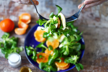 Chef preparing a healthy salad. Male hand mixed salad with mozzarella and tangerine. Salad a la caprese with corn salad and mandarin.