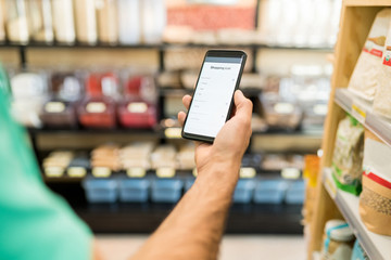 Male Customer Using Mobile Phone In Supermarket
