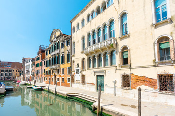 Fototapeta na wymiar Venice. Venetian stone embankments, canals, bridges, parapet, railing and colorful buildings. Palazzo. Architecture details. Authentic venetian canals with boats. Travel tourism vacation in Italy.