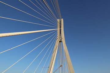 Fototapeta premium Rzeszow, Poland - 9 9 2018: Suspended road bridge across the Wislok River. Metal construction technological structure. Modern architecture. A white cross on a blue background is a symbol of the city